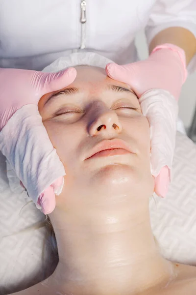 Professionelle Kosmetikerin wäscht den Kunden das Gesicht mit Servietten. — Stockfoto