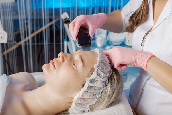 A professional cosmetologist performs an ultrasonic face cleaning procedure for a woman. — Zdjęcie stockowe