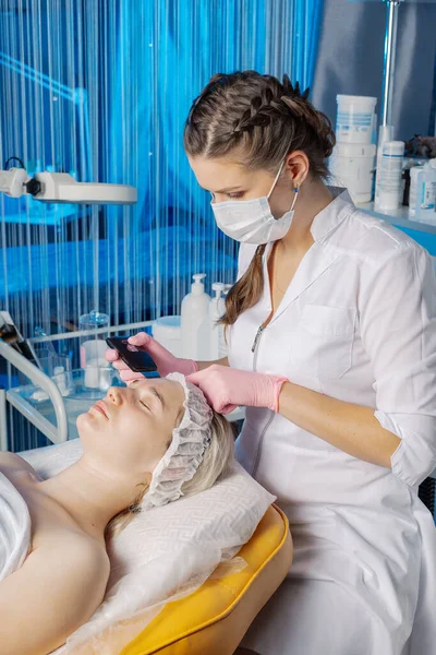 Un cosmetólogo profesional realiza un procedimiento de limpieza facial ultrasónica para una mujer. —  Fotos de Stock