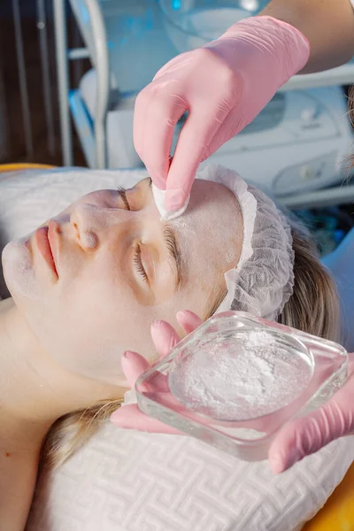 Professional beautician applies talcum powder to womans face. — Stockfoto