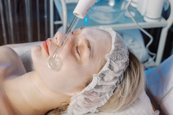 Darsonvalisierung des Gesichts oder Verjüngung des Gesichts mit Hilfe von Elektrotherapie. Foto von darsonval für das Gesicht. Aktuelle Therapie. Die Patientin ist bei der Kosmetikerin. — Stockfoto
