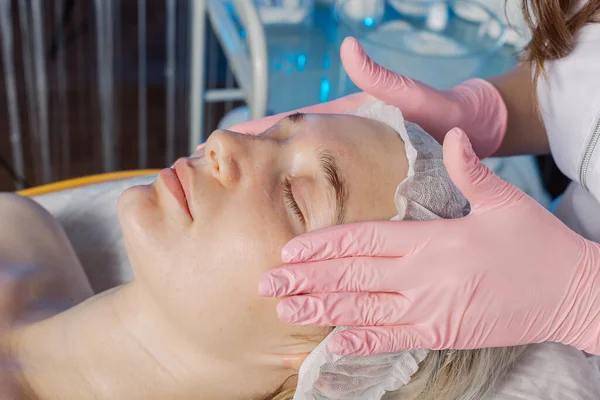 Professional beautician makes a facial massage to a woman. — Stockfoto