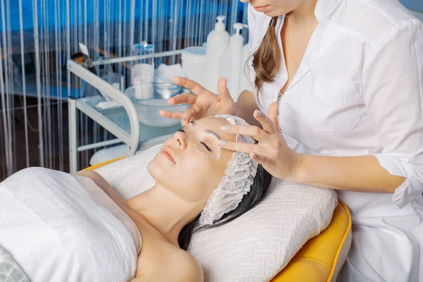 Esteticista profesional hace un masaje facial a una mujer. Fotos de stock