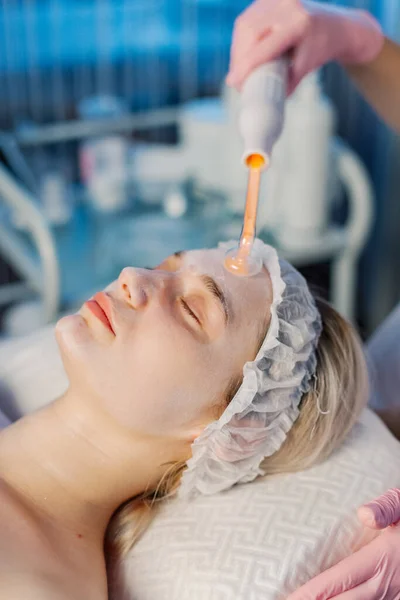 Darsonvalization of the face or rejuvenation of the face with the help of electrotherapy. Photo of darsonval for the face. Current therapy. The patient is at the beautician. Stock Picture