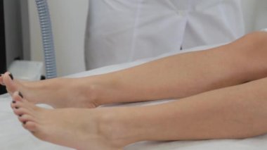 Kadın güzellik uzmanı müşteriye lazer tüy dökücü jel uyguluyor.