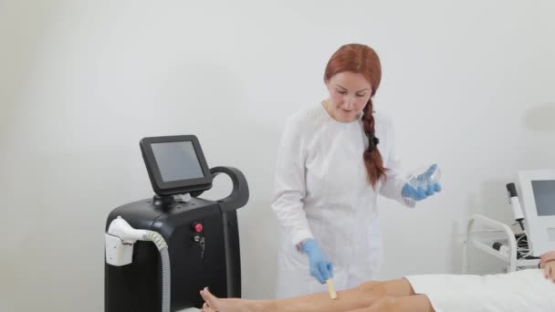 Mujer esteticista aplica gel depilación láser al cliente. — Vídeo de stock