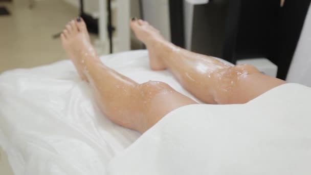 Női kozmetikus teszi lézeres szőrtelenítés a lábak. — Stock videók