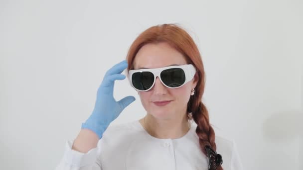 Mujer esteticista profesional se quita las gafas para proteger los ojos del láser. — Vídeo de stock