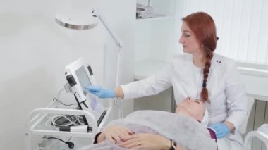 Profesyonel güzellik uzmanı kadın karboksiterapi aletini çalıştırıyor..