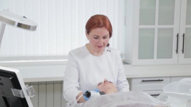 Profesyonel güzellik uzmanı kadın müşterisinin yüzüne karboksiterapi makinesi yapıyor..