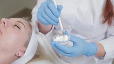 Özel bir konteynırda yüz maskesi karıştıran profesyonel güzellik uzmanı kadın..