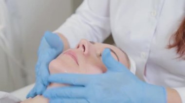 Profesyonel güzellik uzmanı yüzüne sıvı krem sürüyor..