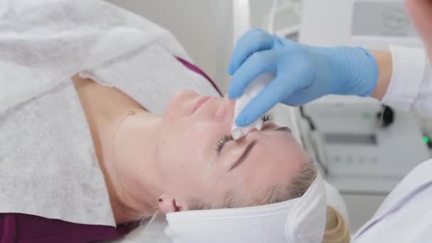 Профессиональная косметолог умывает лицо клиента в косметологическом кабинете. — стоковое видео