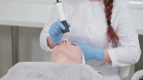 Mujer esteticista profesional haciendo masaje facial con dispositivo de carboxiterapia en el salón de belleza. — Vídeos de Stock