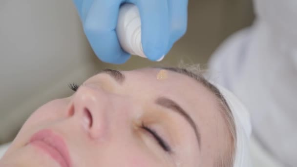 Profesjonalny kosmetyk stosuje krem do twarzy. — Wideo stockowe