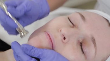 Kadın güzellik uzmanı müşterilerin yüzüne cilt bakımı yapıyor..