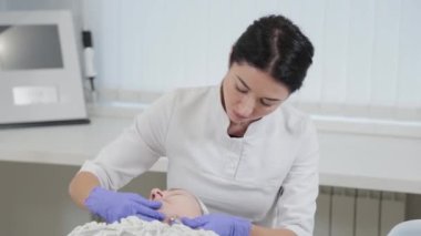 Kadın güzellik uzmanı müşterilerin yüzüne cilt bakımı yapıyor..