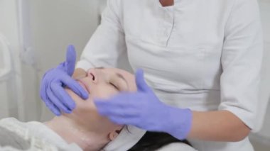 Kadın güzellik uzmanı yüzüne nemlendirici krem sürüyor..