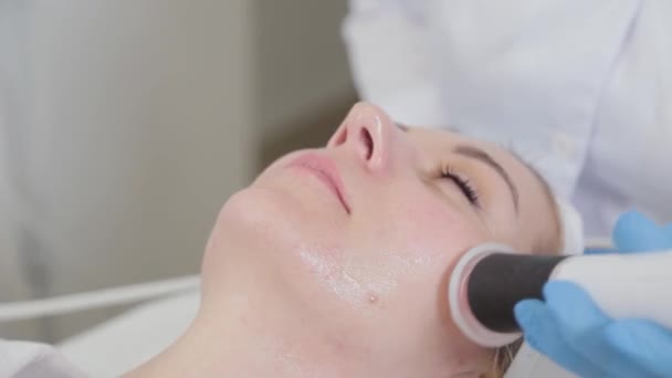 En professionell kosmetolog behandlar en kvinnas ansikte med en karboxyterapi enhet. — Stockvideo