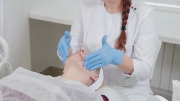 Profesionální kosmetická masáž obličeje ženy v kosmetické klinice. — Stock video