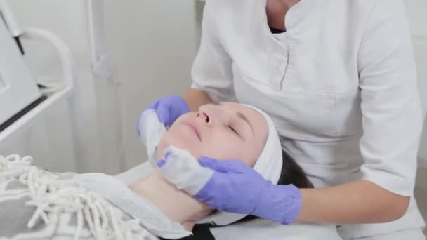 Professionele schoonheidsspecialiste vrouw wast gezicht naar cliënt met servetten. — Stockvideo