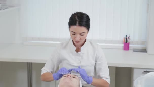 プロの美容師は女性の顔に液体石鹸をこすります. — ストック動画
