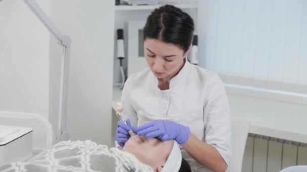 Mujer esteticista realiza procedimiento cosmético dermoabrasión en la cara de los clientes. — Vídeos de Stock