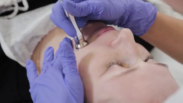 Mujer esteticista realiza procedimiento cosmético dermoabrasión en la cara de los clientes. — Vídeo de stock