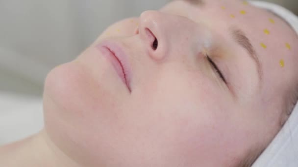 Vrouw schoonheidsspecialiste wrijft helende olie op haar gezicht na de procedure. — Stockvideo