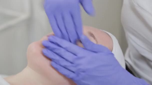 Mujer esteticista frota aceite curativo en su cara después del procedimiento. — Vídeos de Stock