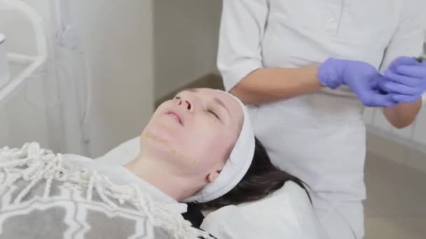 Mujer esteticista frota aceite curativo en su cara después del procedimiento. — Vídeos de Stock
