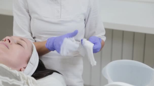 Professional beautician woman washes face to client with napkins. — Stock Video