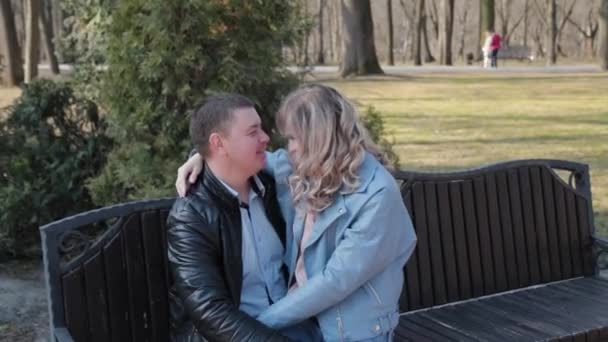 A couple in love in the park on a bench look at each other. — Stock Video