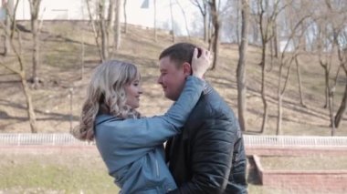 Parkta sevgi dolu bir çift güneşli bir günde korkuluklara sarılıyor..