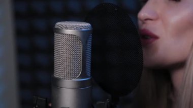 Stüdyoda mikrofona şarkı söyleyen mutlu genç bir kadın..