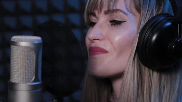 Boldog gyönyörű fiatal nő énekel mikrofonba stúdióban. — Stock videók