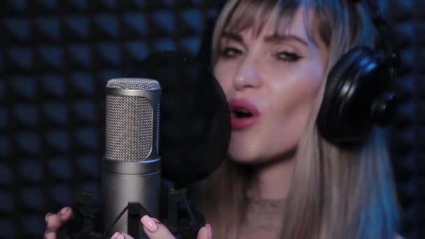 Счастливая красивая молодая женщина поет в микрофон в студии звукозаписи. — стоковое видео