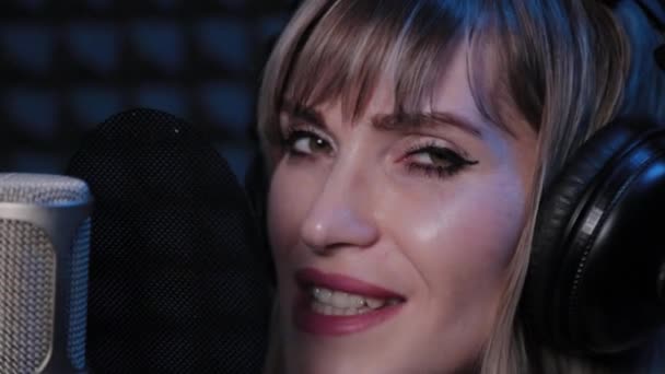 Boldog gyönyörű fiatal nő énekel mikrofonba stúdióban. — Stock videók