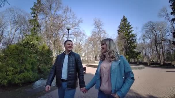 Una pareja enamorada en el parque en un banco se miran. — Vídeos de Stock