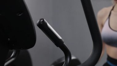 Güzel bir genç kadın spor salonunda bir elipsoide çalışıyor..