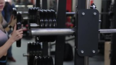 Genç bir kadın spor kulübünde halterlere ağırlık veriyor..