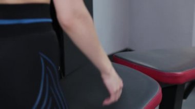 Güzel genç bir kadın spor salonundaki simülatörde bacaklarını çalıştırıyor..