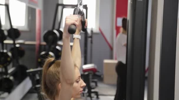 Vacker ung kvinna tränar ryggen på simulatorn i gymmet. — Stockvideo