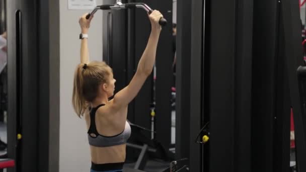 Bella giovane donna che esercita la schiena sul simulatore in palestra. — Video Stock