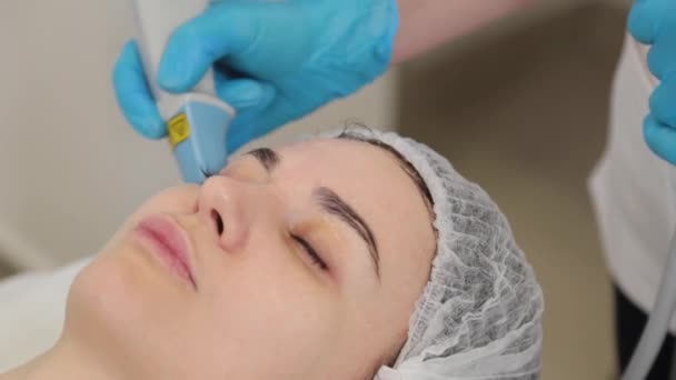 Mujer cosmetóloga trata a los clientes cara con láser. — Vídeos de Stock