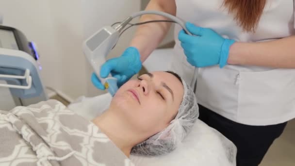 Mujer esteticista haciendo rejuvenecimiento facial con láser. — Vídeo de stock