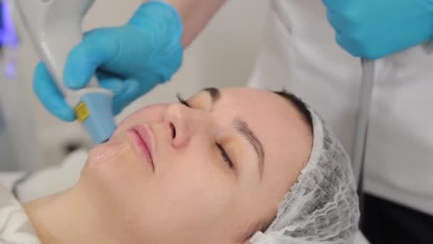 Kobieta kosmetyczka robi laserowe odmładzanie twarzy. — Wideo stockowe