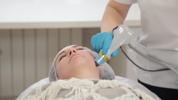 Žena kosmetička si léčí obličej laserem. Omlazení obličeje . — Stock video