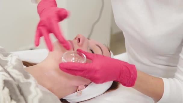 Vrouw schoonheidsspecialiste brengt serum aan op klanten gezicht. — Stockvideo