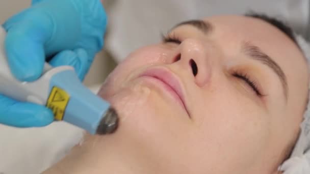 Mujer esteticista haciendo rejuvenecimiento facial con láser. — Vídeo de stock